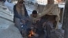 People sit around a fire to warm themselves after a heavy snowfall in Quetta on January 13.