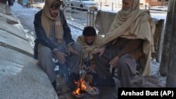 People sit around a fire to warm themselves after a heavy snowfall in Quetta on January 13.