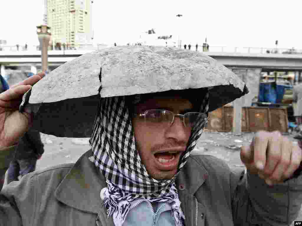 An antigovernment demonstrator covers his head.