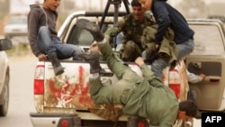 A fleeing rebel falls from a truck driving back to the coastal city of Benghazi.