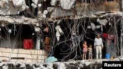 Palestinski muškarac i djeca u ruševinama zgrade u gradu Gazi, 2. novembra 2025.