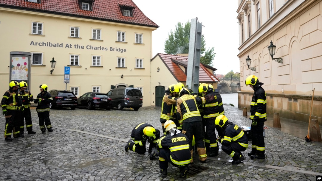Pompierii montează barierele anti-inundație pe insula Kampa de la Praga, în vecinătatea Podului Carol (vizibil printre două clădiri, în plan secund, în dreapta), vineri, 13 septembrie. Cehii se așteaptă ca ploile să țină tot weekendul. 