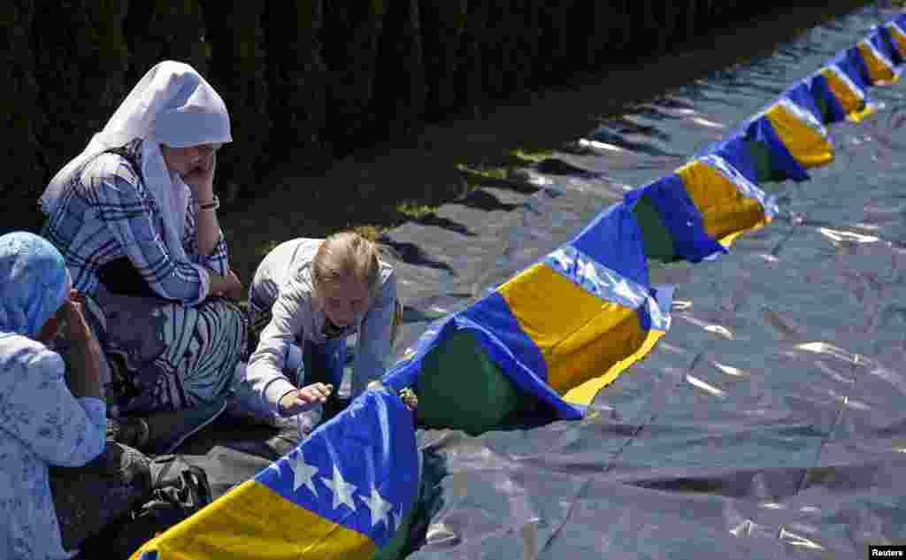 Bosnian Muslim women cry while another touches the coffin of her relative during a mass funeral in the town of Bratunac. Thousands of Bosnians attended the mass funeral in Bratunac for 10 Muslims who were killed by Serb forces at the beginning of the country's 1992-95 war. Their remains were later found and identified in mass graves. (Reuters/Dado Ruvic) 