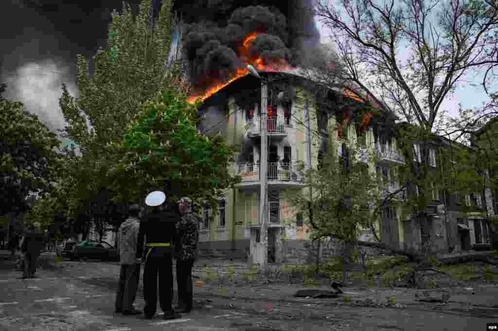 Люди поруч з охопленим вогнем міським управлінням міліції Маріуполя, 9 травня 2014 року