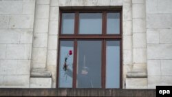 Muškarac stavlja cveće u prozor zgrade Doma sindikata u Odesi