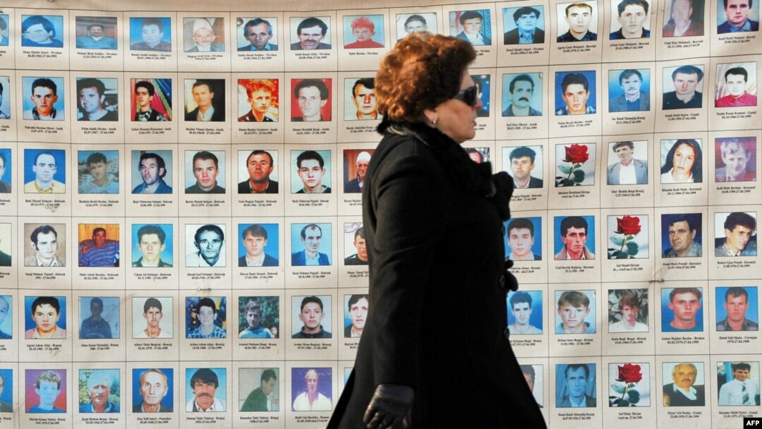 An woman walks past a wall in Pristina on January 25 of photos depicting people missing since the 1998-99 conflict in Kosovo.