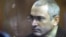 Former Yukos chief Mikhail Khodorkovsky stands behind a glass wall in a courtroom in Moscow during a hearing in 2010.