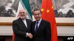 China's Foreign Minister Wang Yi (R) shakes hands with Iran's Foreign Minister Mohammad Javad Zarif during their meeting at the Diaoyutai State Guest House in Beijing on December 31, 2019.