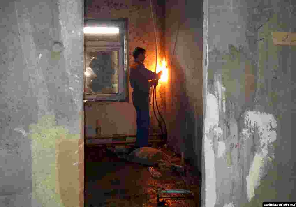 Ýerzeminde ýarylan turbalary kebşirleýän işçi