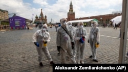 Волонтеры в защитных костюмах и масках очищают территорию Красной площади после книжной ярмарки. 6 июня 2020 года.