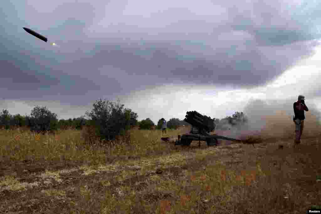 Free Syrian Army fighters cover their ears as they fire a rocket toward government forces in the Deraa countryside. (Reuters/Alaa Al-Faqir) 