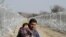 A migrant from Afghanistan holding a child walks next to a border fence at the Macedonian-Greek border in Gevgelija.