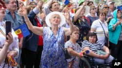 People holding European Union and Moldovan flags dance and sing in Chisinau in May at the end of a rally aiming to show the country's support for EU accession. 