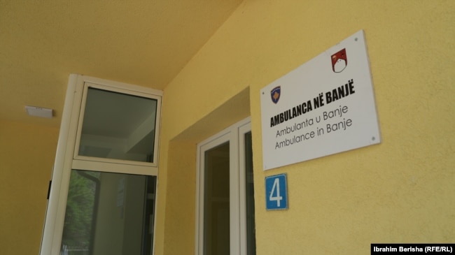 Tabela e sapovendosur në ndërtesën e ambulancës në fshatin Banjë të Skenderajt, tregon emrin e saj në tri gjuhë: shqip, serbisht dhe anglisht, 15 prill 2026.