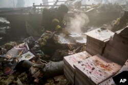 Vatrogasci rade na gašenju požara dok beživotno tijelo leži pod ruševinama nakon što je ruski projektil pogodio veliku štampariju u Harkivu, u Ukrajini, 23. maja.