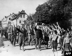Люди приветствуют добровольцев, участвовавших в параде судетских немцев в Свободном корпусе 23 сентября 1938 года недалеко от Аша, Чехословакия, после аннексии немецко-нацистской армией Судетской области Чехословакии