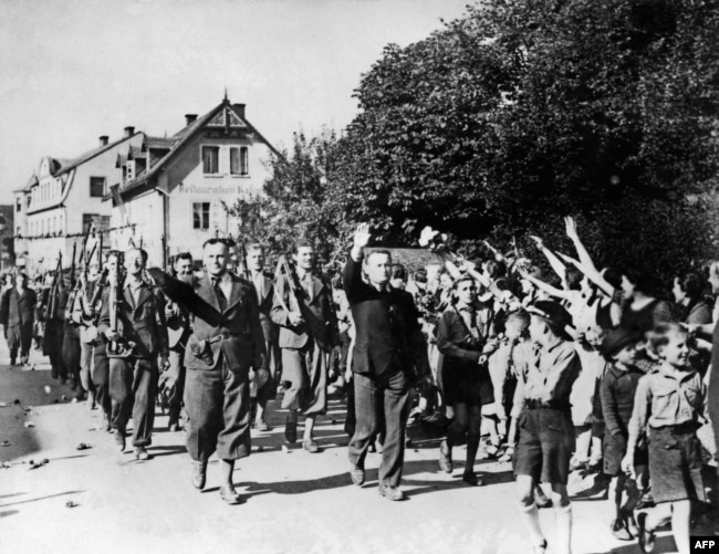 Люди приветствуют добровольцев, участвовавших в параде судетских немцев в Свободном корпусе 23 сентября 1938 года недалеко от Аша, Чехословакия, после аннексии немецко-нацистской армией Судетской области Чехословакии