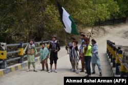 Дети местных афганских жителей с охотничьими ружьями и флагом Панджшерского национального фронта сопротивления (ФНС) стоят над мостом в районе Бандеджой округа Дара в провинции Панджшер, 21 августа 2021 года.