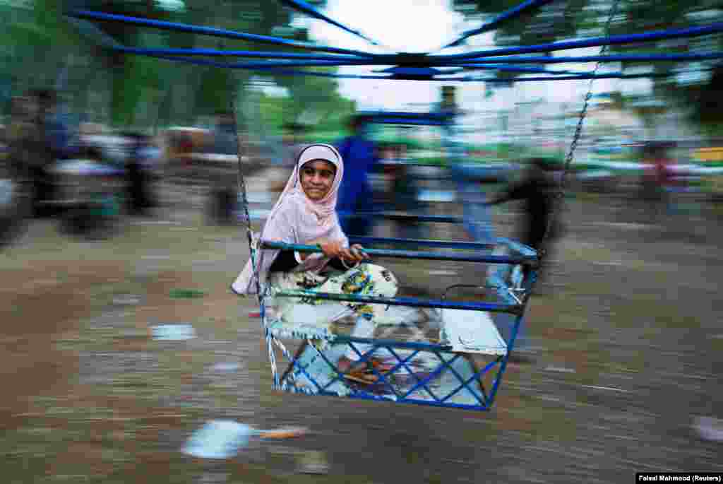 A girl ride swings along a roadside in Rawalpindi, Pakistan. (Reuters/Faisal Mahmood)