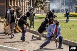 Polițiști kenyeni în civil și soldați iau poziție în fața Parlamentuui din Nairobi în timpul asedierii clădirii de către protestatari, pe 25 iunie.