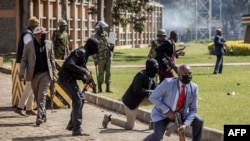 Policijski službenici i osoblje obezbjeđenja štite kenijski parlament dok demonstranti pokušavaju da upadnu u zgradu tokom protesta u centru Nairobija, 25. juni 2024.