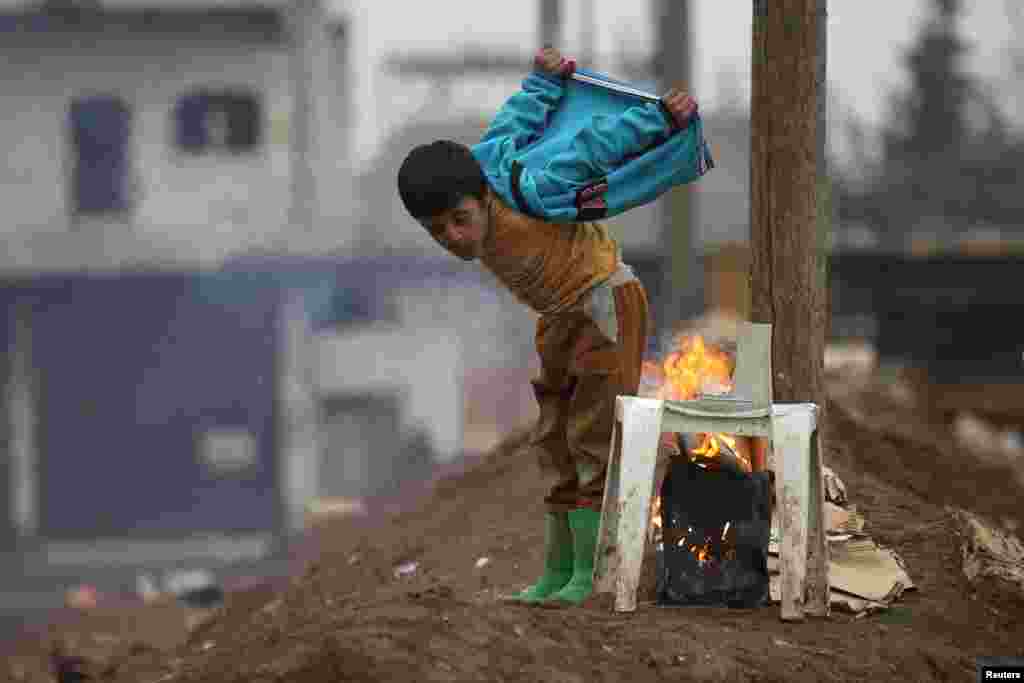 A boy warms himself around a fire in the northern Syrian rebel-held town of Al-Rai. (Reuters/Khalil Ashawi)