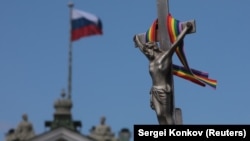 A rainbow ribbon tied to a crucifix is seen next to a Russian flag fluttering atop the State Hermitage Museum during an LGBT rally in St. Petersburg in August.