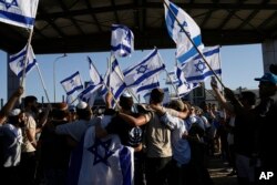 De când cu războiul din Gaza, apărarea drepturilor palestinienilor este văzută de unii israelieni naționaliști ca pierdere de vreme. În imagine: protestatari cu steaguri naționale la baza Sde Teiman, pe 29 iulie.