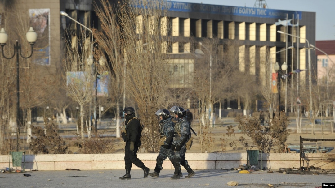 Interior Ministry troops patrol past partially burnt buildings damaged in riots in the town of Zhanaozen.