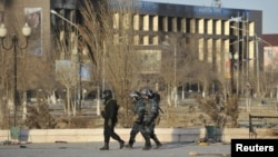 Interior Ministry troops patrol past partially burnt buildings damaged in riots in the town of Zhanaozen.