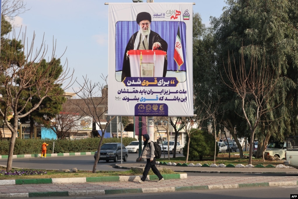A woman walks past a campaign billboard picturing Supreme Leader Ayatollah Ali Khamenei in the holy Iranian city of Qom on February 20.