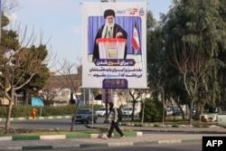 A woman walks past a campaign billboard picturing Supreme Leader Ayatollah Ali Khamenei in the holy Iranian city of Qom on February 20.