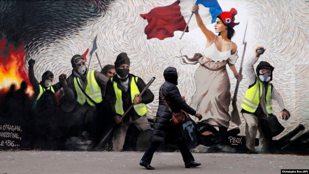 Frescă adaptată cu veste galbene (gilets jaunes) inspirată din pictura lui Delacroix, „La Liberté guidant le Peuple" (Libertatea conducând poporul), în Paris.