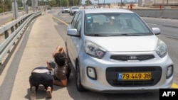 Israelieni adăpostindu-se după mașină pe autostradă lângă Herzliya, în timpul voleului de rachete lansate de Hamas duminică, 26 mai, după-amiază.