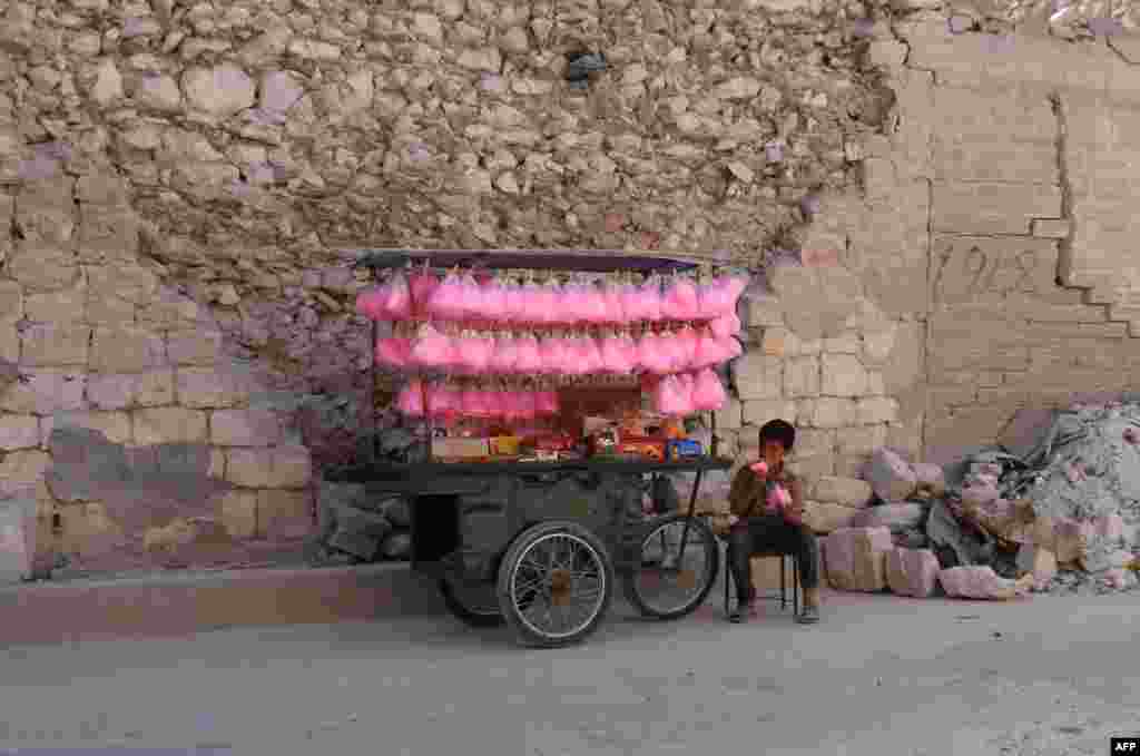 A Syrian child eats cotton candy while selling it on a street cart in the city of Al-Bab in the northern Aleppo Province on May 15. (AFP/Zein Al Rifai)