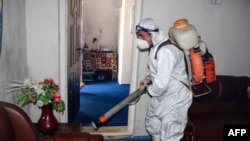 A municipal worker wearing protective gear sprays disinfectant as a preventive measure against the spread of the COVID-19 coronavirus at a local radio station in the northeastern Kunduz Province on June 3.