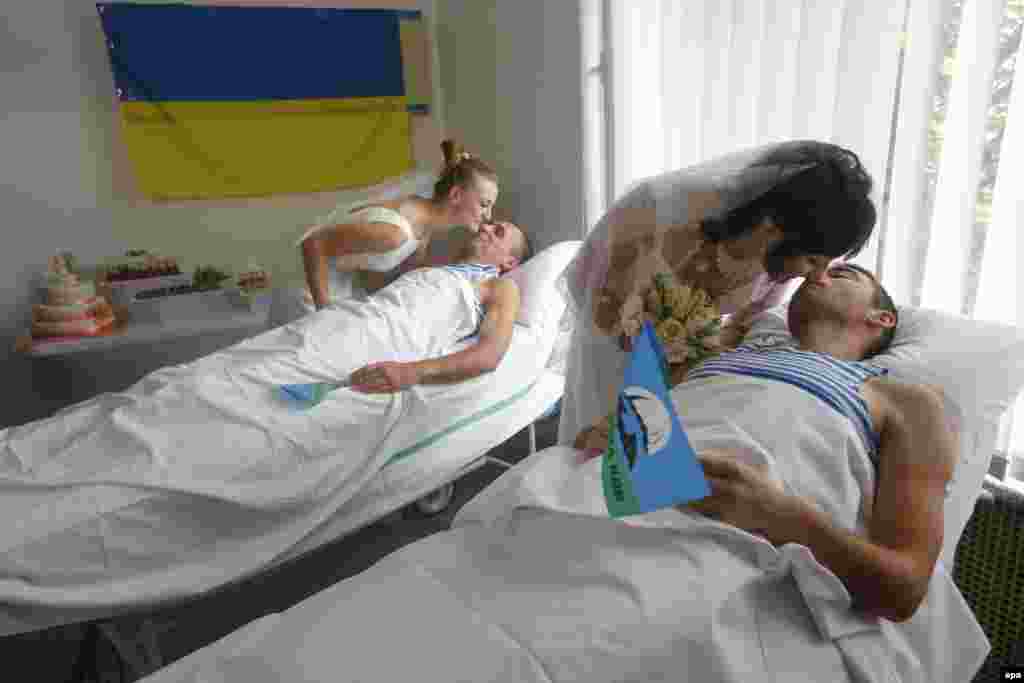 Wounded Ukrainian paratroopers Ruslan Yarish (R) and Oleksandr Ponomaryov kiss their brides during their wedding in the central military hospital in Kyiv, July 9, 2014.