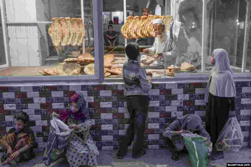 A child buys bread as some children wait for free bread in front of a bakery in Kabul.