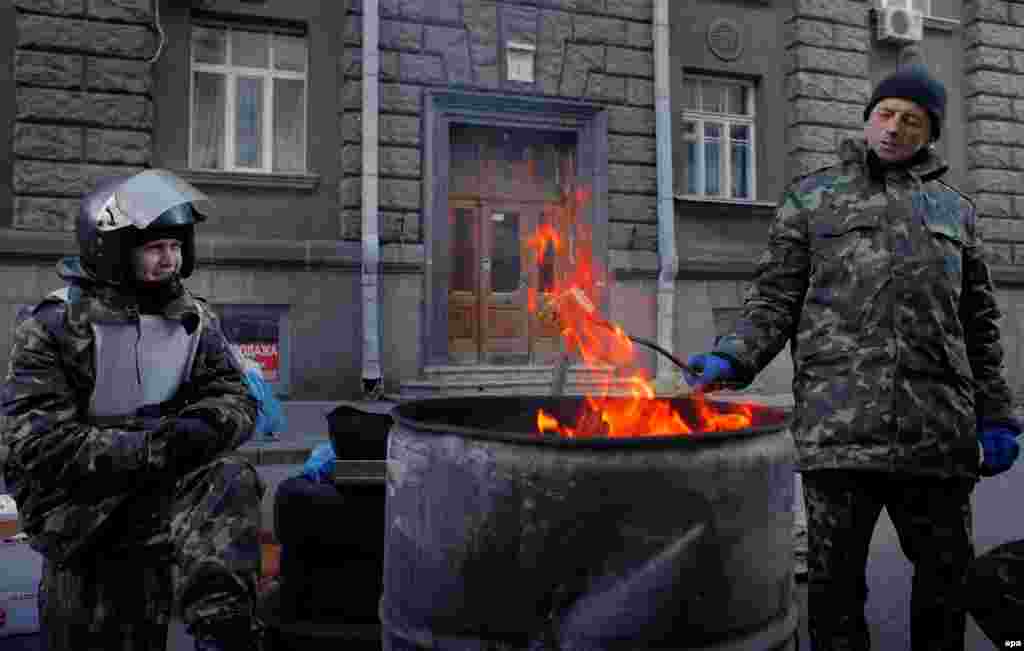 Maidan veterans warm themselves while guarding the entrance to the Presidential Palace near Independence Square.