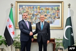 Pakistani Foreign Minister Ishaq Dar (right) shakes hands with his Syrian counterpart, Assad Hassan Al-Shaibani upon his arrival in Islamabad on August 20.