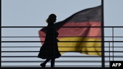 Një grua kalon praë një flamuri gjerman të vendosur në ndërtesën ku gjendet Budestagu. 27 nëntor 2025. 