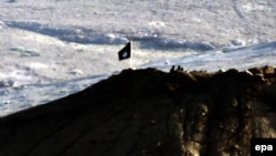 Боевики группировки "Исламское государство" и установленный ими на вершине горы флаг ИГ. Окрестности города Кобани в Сирии, близ границы с Турцией. Октябрь 2014 года.
