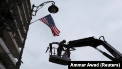 A worker hangs a U.S. flag on a lamppost along a street where the U.S. Consulate in located in Jerusalem.