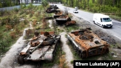 Cars pass by destroyed Russian tanks in a recent battle against Ukrainians in the village of Dmytrivka, close to Kyiv.