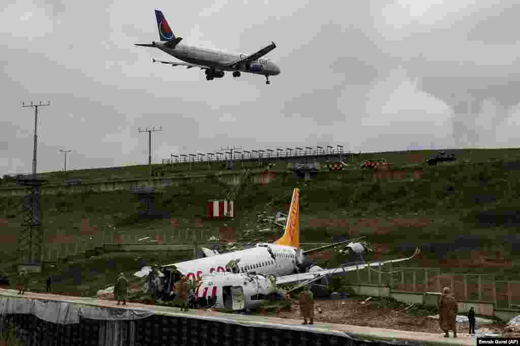 A plane descends to land at Istanbul&#39;s Sabiha Gokcen Airport on February 6 as soldiers guard the wreckage of a plane operated by Pegasus Airlines which had skidded off the runway the previous day.&nbsp;