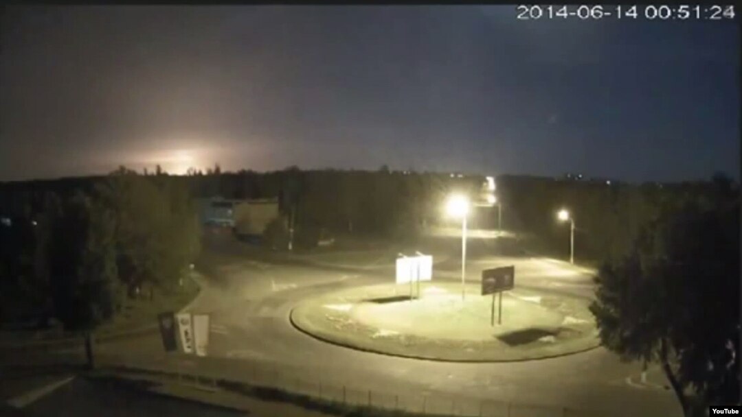 An image from surveillance video posted to YouTube, purportedly of the flash (in distance, left side) as the Ukrainian army IL-76 transport plane crashes to the ground after reportedly being shot down near Luhansk airport early on June 14.