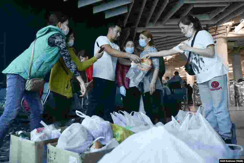 Stranded Kyrgyz migrant workers share bread at Tolmachevo International Airport in Novosibirsk after boxes of food arrive.