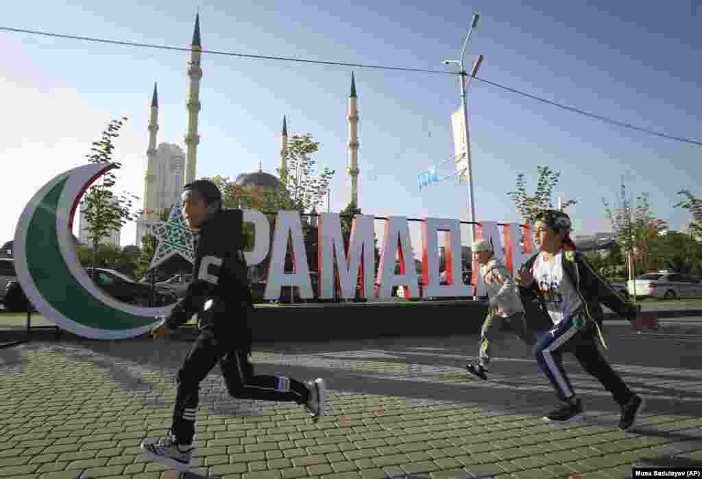 Children run past a sign reading &quot;Ramadan&quot; during Eid celebrations in Grozny, the capital of the Russian republic of Chechnya.&nbsp;