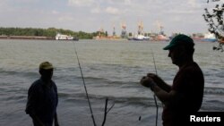Pescari pe malul românesc al Dunării, cu portul Ismail în plan secund. 