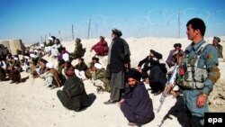 Afghans await remarks by the governor of Helmand Province, Muhammad Naeem Baloch, near the location of the rocket attack on January 1.